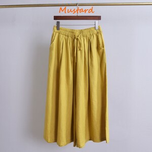 May include: Mustard yellow wide-leg pants with a drawstring waist and side pockets.