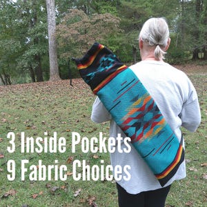 May include: A cylindrical fabric carrying bag featuring a vibrant turquoise, orange, red, and black geometric pattern with a drawstring closure. The bag is worn over the shoulder and displays the text 3 Inside Pockets 9 Fabric Choices.