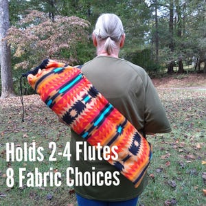 May include: A colorful flute bag with a Southwestern-inspired pattern in orange, black, and turquoise. The bag is held over a person's shoulder. Text on the bag reads: "Holds 2-4 Flutes 8 Fabric Choices."