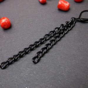 May include: A black chain earring with a double chain design. The chain is made of metal and has a black finish.