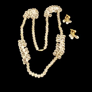 May include: A clear crystal necklace and matching earrings. The necklace is made of faceted beads and has a delicate chain. The earrings are clip-on style.