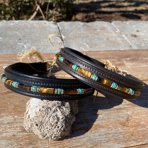 May include: Two black leather horse headbands with brown and turquoise beads. The headbands are decorated with tiger's eye stones.