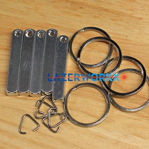 May include: A set of six silver metal bars with a hole at the top, five silver jump rings, and four silver key rings.