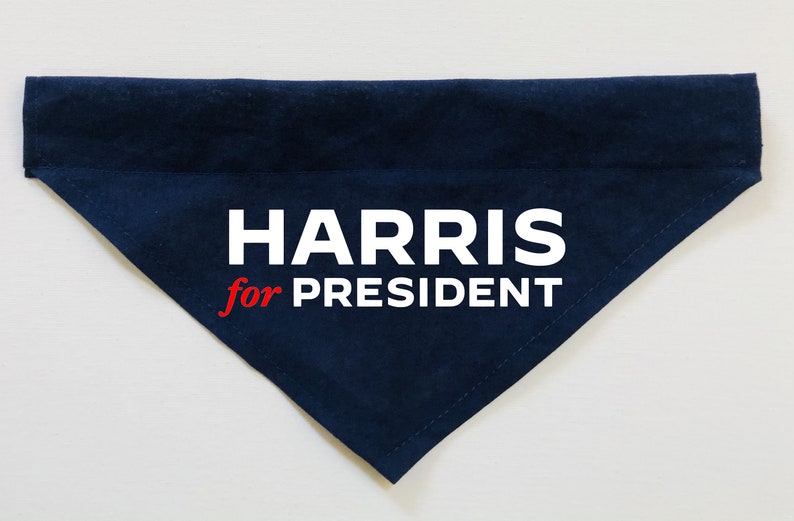Puede incluir: Un bandana para perro de tela azul oscuro con texto blanco que dice "HARRIS for PRESIDENT" en rojo y blanco.