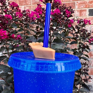 May include: A blue glitter tumbler with a brown lid and a blue straw. The lid has a small brown boat-shaped handle.