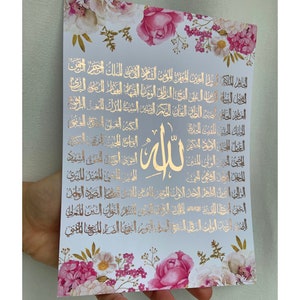 Puede incluir: Un fondo blanco con un diseño floral en rosa y blanco. El fondo tiene una inscripción árabe dorada con la palabra "Allah" en el centro.