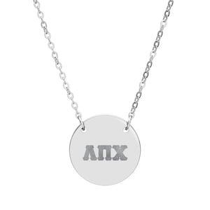 May include: A silver-colored necklace featuring a circular pendant with the Greek letters ΛΠΧ engraved in the center. The pendant is suspended from a delicate chain. The necklace is displayed against a white background.