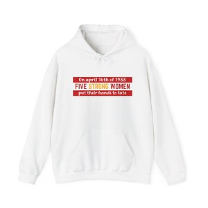 May include: White hooded sweatshirt with a front pocket. The sweatshirt features a red rectangular design with the text "On april 16th of 1988 FIVE STRONG WOMEN put their hands to fate."