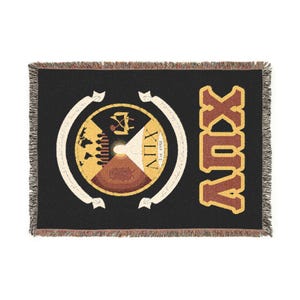 Könnte beinhalten: Schwarze gewebte Wurkdecke mit einem dekorativen kreisförmigen Emblem und dem Wort "XUV" in Braun und Gold. Das Emblem zeigt ein zentrales Design mit Text und einem Banner. Die Decke hat einen Fransenrand.