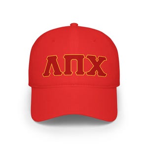 May include: A bright red baseball cap featuring the Greek letters ΛΠX in a bold, blocky font. The letters are a deep red with a gold outline, creating a striking contrast against the cap's solid color.