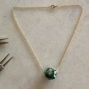 May include: A gold chain necklace with a turquoise and brown gemstone pendant.