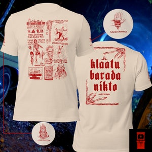 May include: Cream-coloured t-shirt with red graphic illustrations and text. The front has various drawings and text, while the back displays "klaatu barada nikto" in bold letters. A unique and artistic design.