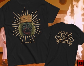 May include: Black t-shirt with a gold illustration of a demon king wearing a crown and the word "PAIMON" underneath. The back of the shirt has a gold sigil.