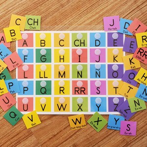 May include: A colorful alphabet chart with letter tiles in various colors. Each tile has a letter and a phonetic pronunciation. The chart is on a white background.
