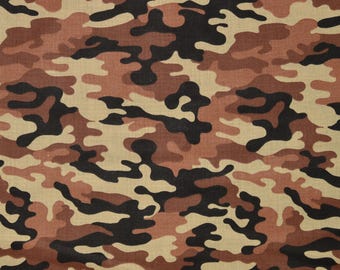 May include: Camouflage fabric in shades of brown, tan, and black. The pattern features irregular shapes and splotches, with a ruler along the bottom showing measurements in inches.