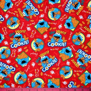 Peut inclure: Tissu rouge avec un motif répété de Cookie Monster tenant des biscuits. Le texte "Me Want Cookie!" est répété sur tout le tissu.