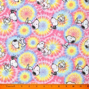 May include: A pink fabric with a tie-dye pattern featuring multiple white cartoon dogs in various poses. The dogs are all wearing a black collar and have a white outline.