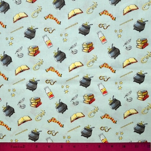 May include: A blue fabric with a repeating pattern of various Harry Potter themed images, including cauldrons, books, wands, glasses, feathers, and stars.
