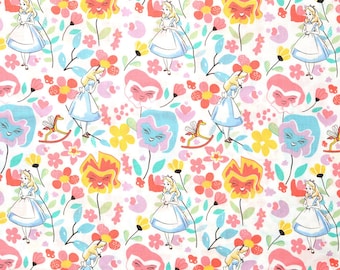 Puede incluir: Tela blanca con un patrón repetido de personajes de Alicia en el País de las Maravillas y flores. Alicia está representada con un vestido azul y un delantal blanco, y las flores son de color rosa, amarillo y azul.