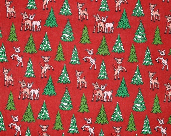 Op de afbeelding: Rode stof met een herhalend patroon van groene kerstboom en bruine rendieren met rode strikken. De stof wordt gemeten met een liniaal.