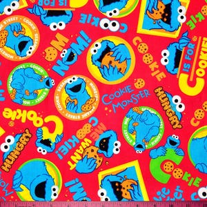 Könnte beinhalten: Roter Stoff mit einem sich wiederholenden Muster der Cookie Monster-Figur aus der Sesamstraße. Das Design umfasst Cookie Monster mit Keksen, die Wörter "Cookie Monster", "Hungry", "Nom!" und "Cookie is for".
