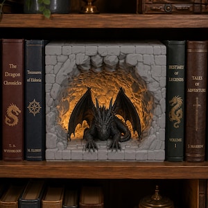 Pode incluir: Um inserto para estante apresentando uma escultura de dragão cinza-escuro dentro de uma estrutura de caverna de pedra cinza-claro. O interior da caverna é iluminado com uma luz amarela quente, destacando as asas e as escamas do dragão.
