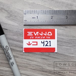 May include: A red square sticker with white text and a black arrow pointing down. The text reads "EVNJO", "LV SK 1", and "421".