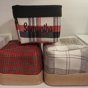 May include: Three plaid storage bins with a black fabric top. The top bin has the name Samantha written on it. The bins are stacked on top of each other.