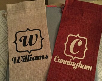 May include: Two personalized burlap gift bags. One bag is beige with black lettering and the name "Williams" and the other bag is red with white lettering and the name "Cunningham".
