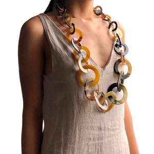 Könnte beinhalten: Eine lange Halskette aus großen, miteinander verbundenen Hornringen in Braun-, Schwarz- und Gelbtönen.