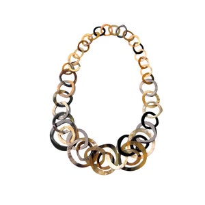 Puede incluir: Un collar dorado, marrón y negro hecho de círculos enlazados y superpuestos.