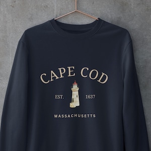 May include: A navy blue sweatshirt with a white graphic of a lighthouse and the text "CAPE COD EST. 1637 MASSACHUSETTS".