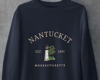 Könnte beinhalten: Ein dunkelblaues Sweatshirt mit Rundhalsausschnitt und einem Grafikdruck mit dem Text NANTUCKET, EST. 1641 und MASSACHUSETTS in hellbeiger Schrift. Das Design zeigt einen weißen Leuchtturm mit roter Spitze und grünen Bäumen auf einem Felsensockel.