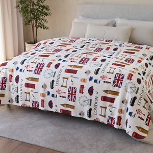 Pode incluir: Um edredom branco com um padrão repetido de marcos de Londres, incluindo a bandeira da União Jack, cabines telefônicas vermelhas, ônibus de dois andares e o London Eye.