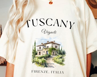 May include: A white t-shirt with a graphic print of a Tuscan villa with the text "Tuscany Vigneti Firenze. Italia" printed on the front.
