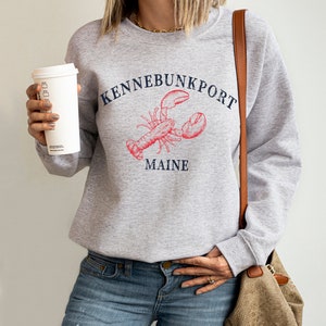 May include: Gray sweatshirt with a red lobster illustration and the text "Kennebunkport Maine".