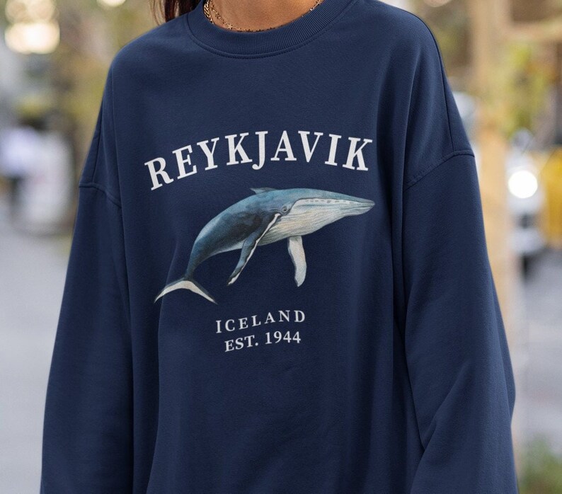 May include: A navy blue sweatshirt with a white whale graphic and the text "REYKJAVIK ICELAND EST. 1944".