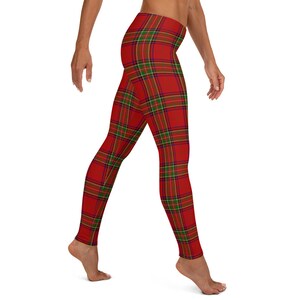 May include: Full-length leggings featuring a vibrant red base color with a classic tartan plaid pattern. The plaid design consists of intersecting thin lines in shades of forest green, navy blue, and yellow, creating a repeating grid across the fabric.
