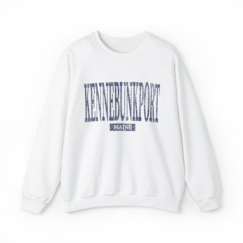 K&ouml;nnte beinhalten: Ein wei&szlig;es Sweatshirt mit Rundhalsausschnitt und dem Text "KENNEBUNKPORT" in verblichenen marineblauen Buchstaben auf der Brust. Darunter befindet sich ein kleineres Rechteck mit dem Wort "MAINE" in Marineblau. Das Sweatshirt hat lange &Auml;rmel.