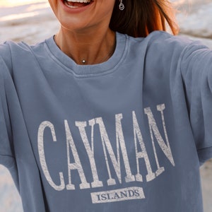 May include: A light blue sweatshirt with the text "CAYMAN ISLANDS" printed in white.