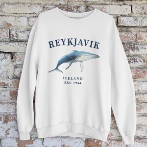 May include: White sweatshirt with a blue whale graphic and the text "REYKJAVIK ICELAND EST. 1944"
