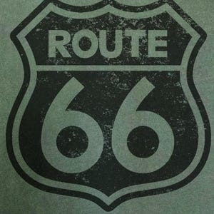 Puede incluir: Una superficie de tela verde oliva oscuro con un gr&aacute;fico negro de estilo desgastado del ic&oacute;nico emblema de escudo de la Ruta 66. El dise&ntilde;o incluye la palabra ROUTE en letras may&uacute;sculas negritas sobre el n&uacute;mero 66, todo dentro de un borde de escudo.
