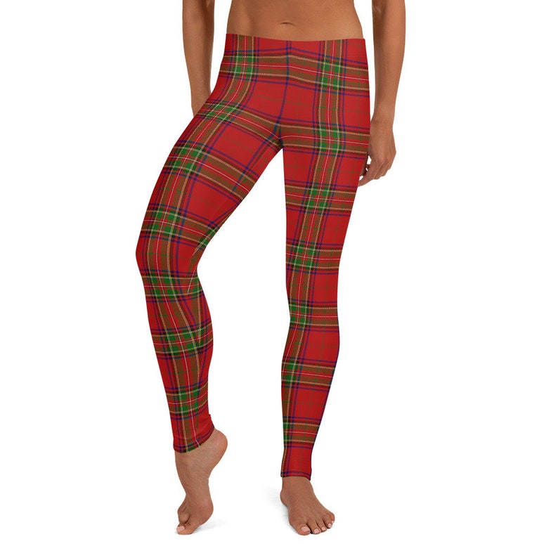 May include: Full-length leggings featuring a vibrant red base color with a classic tartan plaid pattern. The design incorporates intersecting thin lines in shades of forest green, navy blue, and golden yellow, creating a repeating grid across the fabric.