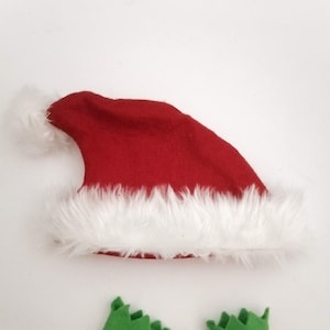 May include: A red felt Santa hat with a white fur trim and a white pom-pom on top. Two green felt elf shoes with pointed toes.