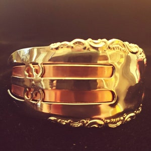 May include: A gold-toned metal bracelet with a decorative design and three copper bands.