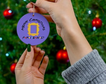 May include: Purple Christmas ornament with the words "Merry Christmas" and "Friend" surrounding a yellow frame from the TV show "Friends".
