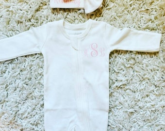 Puede incluir: Mono blanco para bebé con un monograma rosa "K.S.B." y un gorro blanco de punto con un lazo y el nombre "Kennedy" bordado.