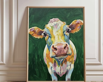 May include: A framed painting of a cow with a colorful, impressionistic style. The cow's face is the focal point, with a pink nose, yellow and orange fur, and a green background. The artwork is displayed in a wooden frame.