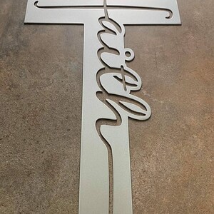 Peut inclure: Une croix en m&eacute;tal argent&eacute; avec le mot "foi" d&eacute;coup&eacute; dans une &eacute;criture d&eacute;corative.