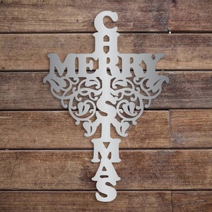 May include: A silver metal Christmas sign with the words "Merry Christmas" in a decorative font. The sign is shaped like a cross with the word "Merry" across the top and the word "Christmas" down the center.